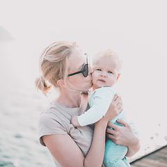 Image showing Tender woman caressing her little baby boy infant child outdoors. Mother's unconditional love for her child