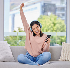 Image showing Woman, excited and phone with headphones for music on a home sofa with happiness and energy. Happy female person on a lounge couch with a smartphone for streaming or listen to audio, podcast or radio
