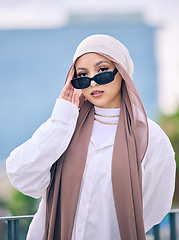 Image showing Portrait, fashion or sunglasses with a muslim woman in dubai wearing a cap and scarf for contemporary style. Islamic, faith and hijab with a trendy young arab person posing outside in modern eyewear