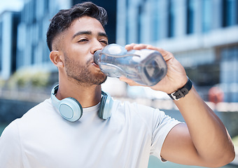 Image showing Man, fitness and drinking water in city after exercise, cardio workout or training outdoors. Thirsty male person, athlete or runner with drink for hydration, rest or break from run in an urban town