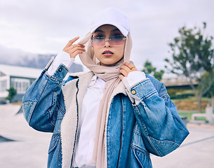 Image showing Portrait, sunglasses or religion with a muslim woman outdoor in a cap and scarf for contemporary style. Islam, fashion or hijab with a trendy young arab female person posing outside in modern clothes