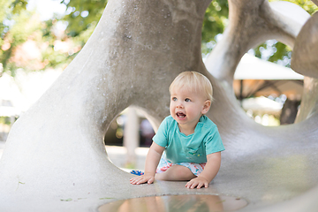 Image showing Child playing on outdoor playground. Toddler plays on school or kindergarten yard. Active kid on stone sculpured slide. Healthy summer activity for children. Little boy climbing outdoors.