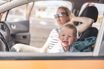 Image showing Mother and her infant baby boy child on family summer travel road trip, sitting at dad's front seat, waiting in the car for father to buy farry tickets.