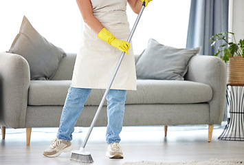 Image showing Cleaning, broom and sweeping with a housekeeper in the living room of a home for housework or chores. Floor, sweep and housekeeping with a cleaner in a house to tidy for hygiene during a spring clean