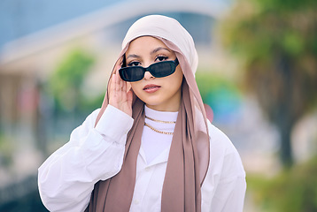 Image showing Portrait, fashion or sunglasses with an arabic woman outdoor in a cap and scarf for contemporary style. Islam, faith and hijab with a trendy young muslim person posing outside in modern eyewear