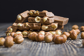 Image showing bitter real chocolate, photographed close-up with whole hazelnuts inside and next to a bar of broken chocolate