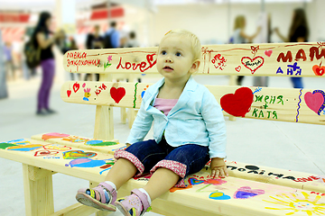 Image showing little fashionable baby sits on the painted bench