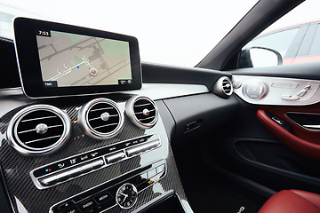 Image showing View from inside a car on a part of dashboard with a navigation unit and blurred street in front of a car