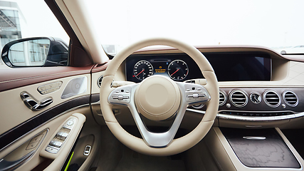 Image showing Car interior luxury. Interior of prestige modern car. Leather comfortable seats, dashboard and steering wheel. White cockpit with exclusive wood and metal decoration