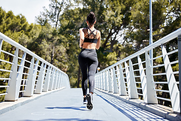 Image showing Woman, fitness and running on bridge for exercise, cardio workout or training in nature outdoors. Rear view of fit, active and sports female person, athlete or runner exercising for healthy wellness