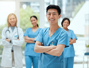 Image showing Portrait, medical and an asian man nurse arms crossed, standing with his team in a hospital for healthcare. Leadership, medicine and teamwork with a male health professional in a clinic for treatment