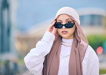 Image showing Portrait, fashion or sunglasses with a muslim woman in saudi arabia wearing a cap and scarf for contemporary style. Islam, faith and hijab with a trendy young arab person posing outside in shades