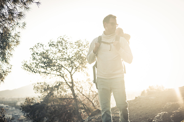 Image showing Young father carrying his infant baby boy son in backpack while tracking around Malaga, Spain in sunset. Family travel and vacation concept