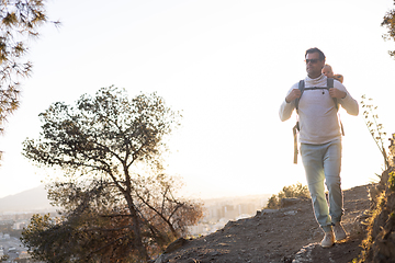 Image showing Young father carrying his infant baby boy son in backpack while tracking around Malaga, Spain in sunset. Family travel and vacation concept