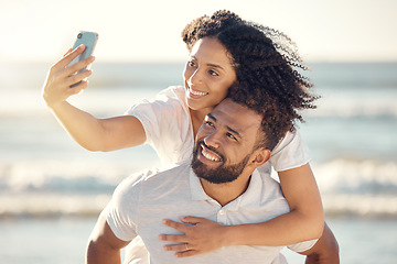 Image showing Couple, piggyback and selfie at beach, smile and happy on holiday with summer sunshine for blog, post and web. Man, woman and photography for romantic vacation, profile picture and social media app