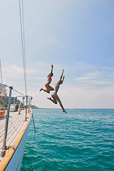 Image showing Summer, sailing and friends jumping off a yacht together into the ocean for freedom, fun or swimming. Travel, energy and bikini with girls leaving a boat to jump into the sea while on a luxury cruise