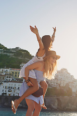 Image showing Vacation piggyback, free and women in summer for freedom, city adventure and walking in Spain. Smile, travel and young friends being carefree together on a holiday in a small town by the ocean