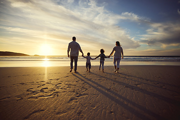 Image showing Sunrise, beach and back of family holding hands and walking on holiday, summer vacation and weekend. Nature, travel and mother, father and children by ocean for bonding, adventure and quality time