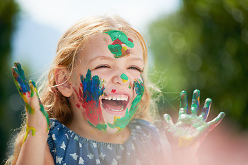 Image showing Happy, little girl covered in paint and outdoors with a lens flare. Happiness or creative, playing or art fun and cheerful or excited young child with painting over her face outside in the summer