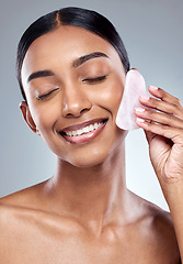Image showing Beauty, smile and gua sha with face of woman in studio for massage, wellness and cosmetics. Spa, self care and glow with model on grey background for facial, cosmetology and rose quartz crystal