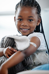 Image showing African girl kid, vaccine and portrait with smile, medicine or happiness on sofa for wellness in hospital. Female child, happy or excited with plaster for injection, healthcare or brave to stop virus