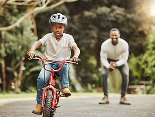 Image showing Boy on bicycle, father cheers and learning cycling with help, helmet for safety and family in park. Support, motivation and trust, black man and young kid outdoor, teaching and learn bike riding