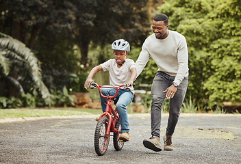 Image showing Black family, father teaching child cycling in park with bicycle and helmet for safety, learning and help. Support, motivation and trust, man with boy outdoor and learn bike riding with mockup space