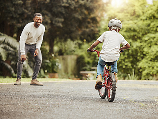 Image showing Boy on bicycle, father cheers and learn cycling with help, helmet for safety and family in park. Support, motivation and trust, black man and young kid outdoor, teaching and learning bike riding