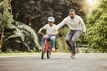 Image showing Family, father teaching child cycling in park with bicycle and helmet for safety, learning and help. Support, motivation and trust, black man with boy outdoor and learn bike riding with mockup space