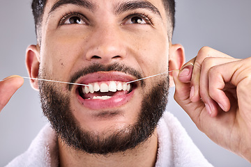 Image showing Face, dental and man floss teeth in studio isolated on a white background. Tooth, flossing product and male model cleaning for oral wellness, fresh breath and healthy hygiene to stop gingivitis.