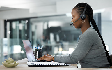 Image showing Black woman, laptop and call center in customer service, telemarketing or support at the office desk. African female person, consultant or agent typing on computer with headphones for online advice