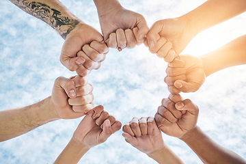 Image showing Hands in circle, fist and blue sky, community in collaboration for support and diversity together from below. Teamwork, power hand sign and sunshine, positive group of people in solidarity and huddle