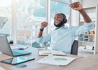 Image showing Happy black man at desk with headphones, music and enjoying work with excited dance at desk with tech. African businessman in modern office with earphones, dancing and fun working on startup report.