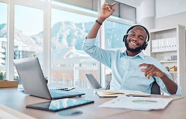 Image showing Dance, happy man at desk with headphones, music and enjoying work with online radio streaming service. African businessman in modern office with earphones, dancing and fun working on startup report.