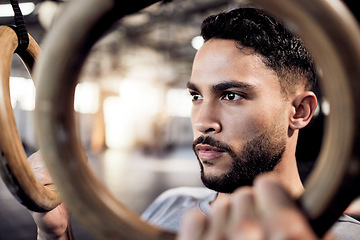 Image showing Athlete man, gymnastic rings and gym for a training workout with focus and commitment. Face of serious male person with pull up exercise for strong muscle, power and fitness training with balance