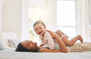 Image showing Mom lying, lift newborn and bed with smile, care and happiness in morning with love, bond or excited face. Young mother, baby and happy in bedroom, family home and holding kid with pride in sunshine