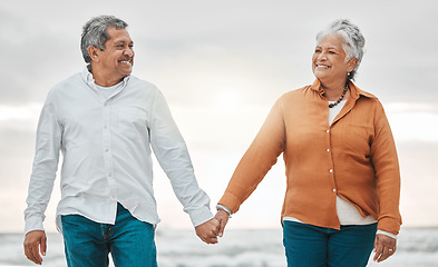 Image showing Senior happy couple, walk beach and holding hands for smile, bond and care with romance, love and vacation. Elderly man, woman and sunset with happiness, retirement and travel by ocean for holiday