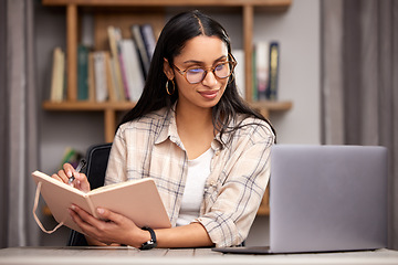 Image showing Laptop, notebook and learning with a student woman in a university library to study for a final exam. Technology, education and diary with a young female college pupil reading research material