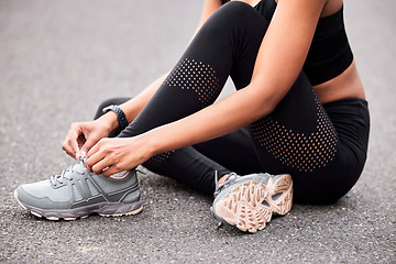 Image showing Fitness, woman tying shoes and sitting road for safety during outdoor marathon training. Running, cardio health and wellness, female athlete fixing laces on footwear and feet of runner on asphalt.