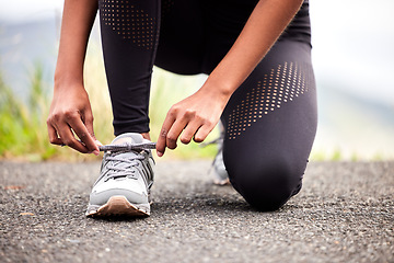 Image showing Sport, feet of woman tying sneakers and runner on road for safety during outdoor marathon training. Running, cardio health and wellness, female athlete fixing laces on footwear and closeup of asphalt