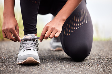 Image showing Fitness, feet of woman tying shoes and runner on road for safety during outdoor marathon training. Running, cardio health and wellness, female athlete fixing laces on footwear and closeup of asphalt.