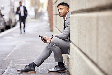 Image showing Thinking, phone and a businessman sitting in the city for social media, communication or email. Contact, ideas and a corporate person in a suit with a mobile for a chat, internet or notification