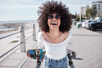 Image showing Woman, happy and outdoor with a skateboard for travel, adventure and freedom on a beach road. Face of comic african person laugh on promenade for tropical vacation or skating with sunglasses in Miami