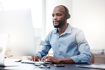 Image showing Black man typing at computer, call center and contact us, communication and concentrate with headset. Male agent with focus, customer service and help desk employee with online support and email