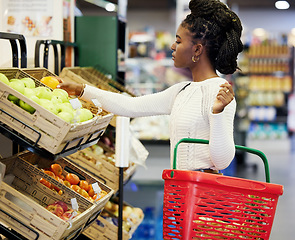 Image showing Black woman, supermarket and shopping for fruit, choice or discount for health, diet or nutrition in customer experience. Plastic basket, grocery store or mall for retail, sales or girl with decision