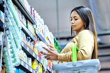 Image showing Grocery, shopping and choice with woman in supermarket for food, retail or label reading. Product, nutrition and health with female customer and basket in store for diet, discount and price inflation