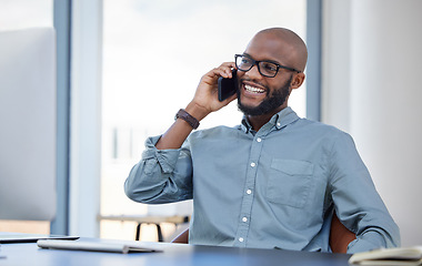 Image showing Happy, businessman with smartphone and on a phone call at his desk with computer in workplace office. Online communication, smile and African man with cellphone talking at his modern workspace