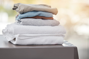 Image showing Home, clothes on a washing machine and laundry day with a lens flare. Cleaning or hygiene, appliances or mockup space and folded clean pile of clothing on a wash dryer at a house for housework