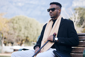 Image showing Blind black man, park bench and outdoor with sunglasses, walking stick or relax by trees, peace or thinking. African guy, vintage fashion and young person with disability, glasses or travel in nature