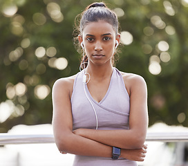 Image showing Serious portrait of fitness woman with earphones in park, commitment and listening to music or podcast. Exercise, training and girl with headphones and focus for radio streaming and running in nature